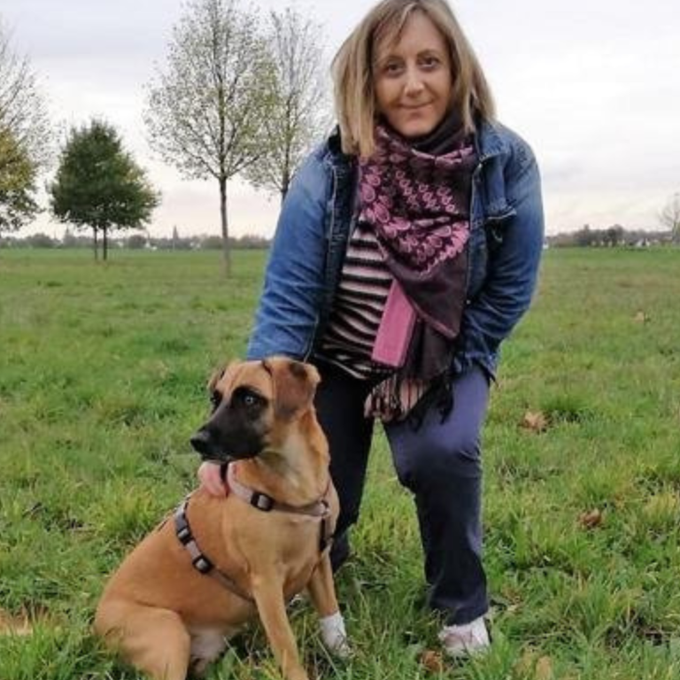 Julia Frau steht mit Hund auf einer Wiese